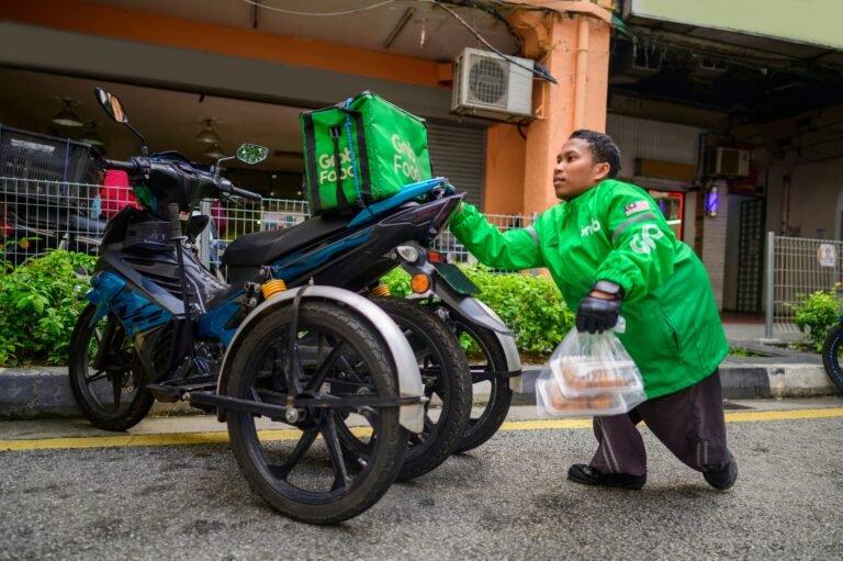 A Grab delivery rider with an electric motorcycle in Singapore, representing commercial operators who can claim Singapore's EV grants