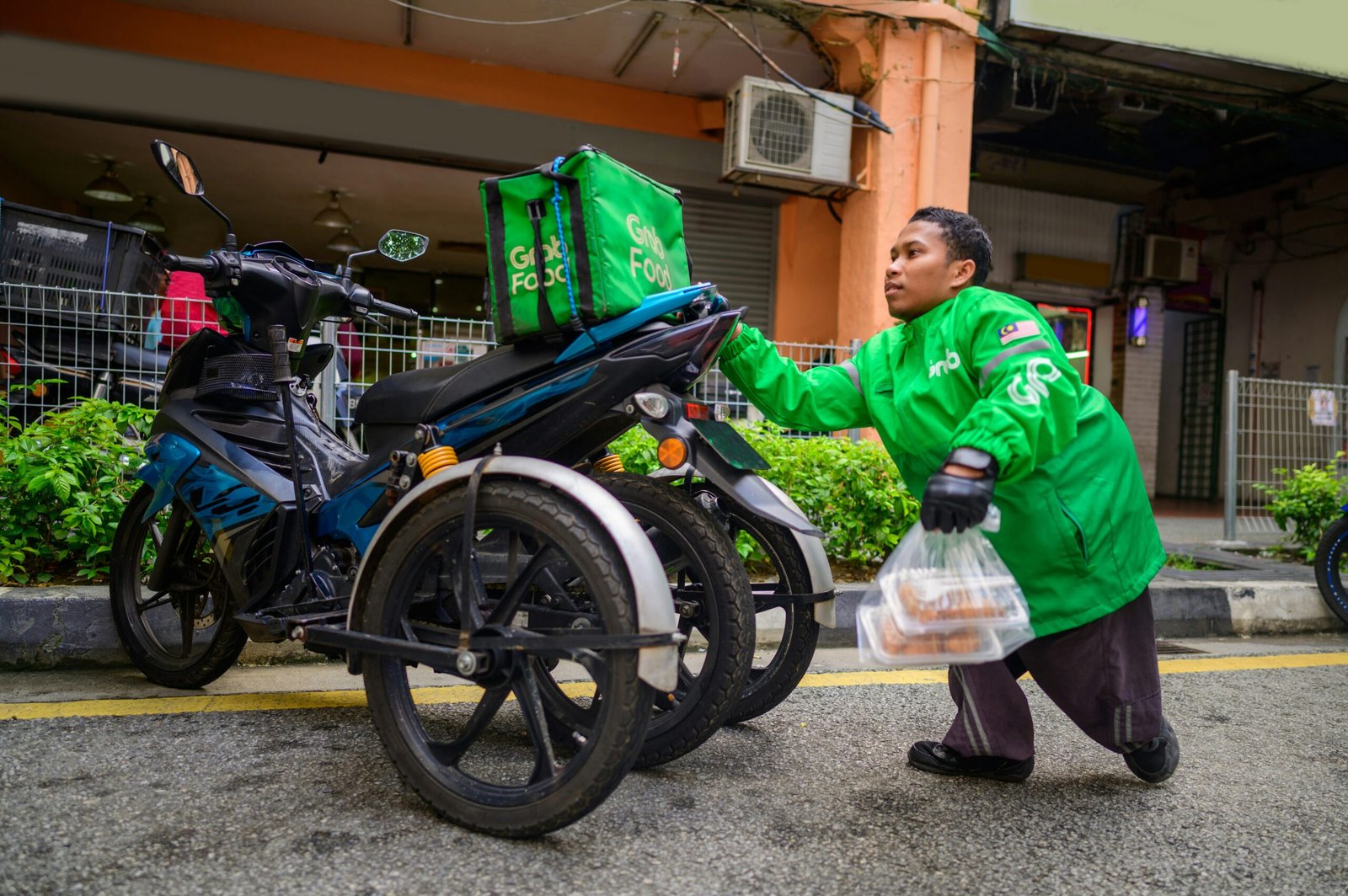 A Grab delivery rider with an electric motorcycle in Singapore, representing commercial operators who can claim Singapore's EV grants