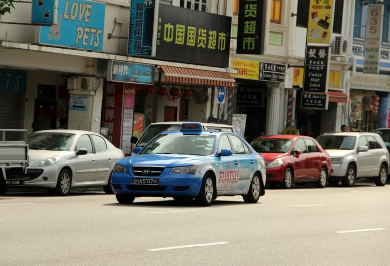 Blue taxi driving on a Singapore street, a commercial vehicle type affected by COE and PQP renewal decisions