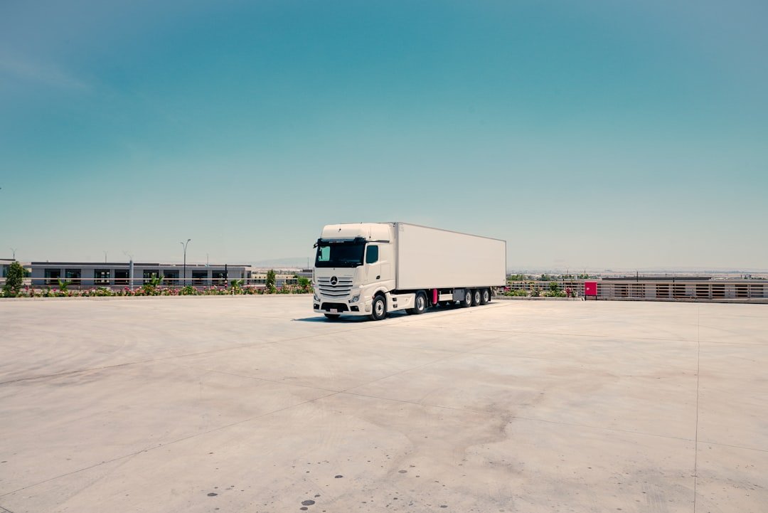 White commercial truck and trailer parked at a construction supply yard, representing the general lorry pool in a Singapore construction fleet
