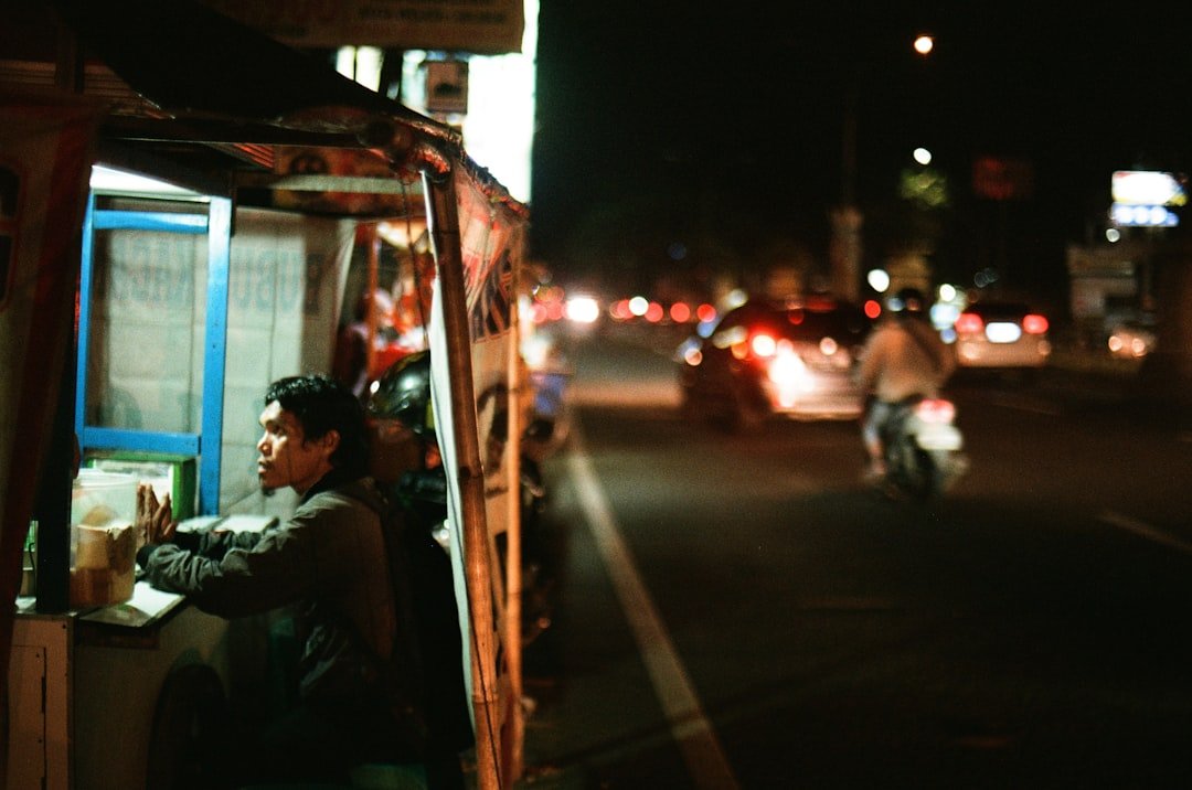Asian driver resting near his vehicle at night, illustrating the need for scheduled rest breaks in commercial driver fatigue management