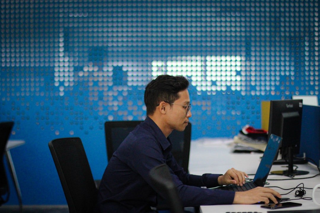 Fleet manager working at a desk with computer monitors, reviewing telematics and vehicle tracking data for a Singapore commercial fleet