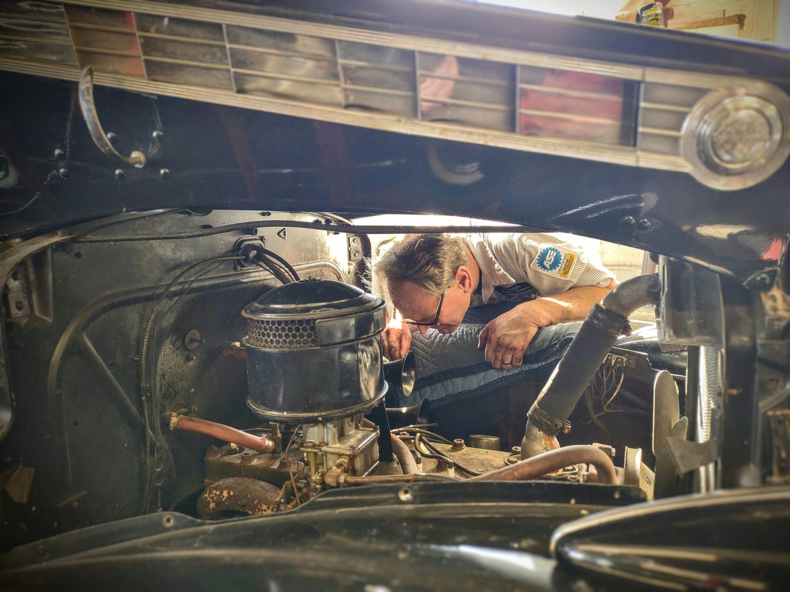 Mechanic inspecting a vehicle engine bay in a workshop, part of assessing an ageing commercial vehicle before an insurance renewal decision