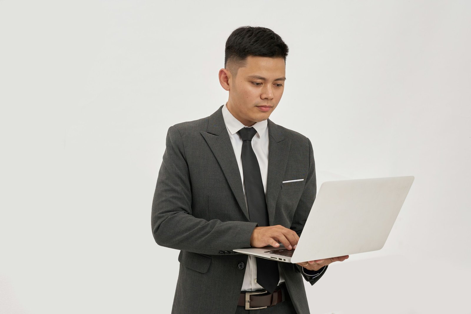 Asian businessman typing on a laptop while reviewing commercial vehicle insurance policy options in an office