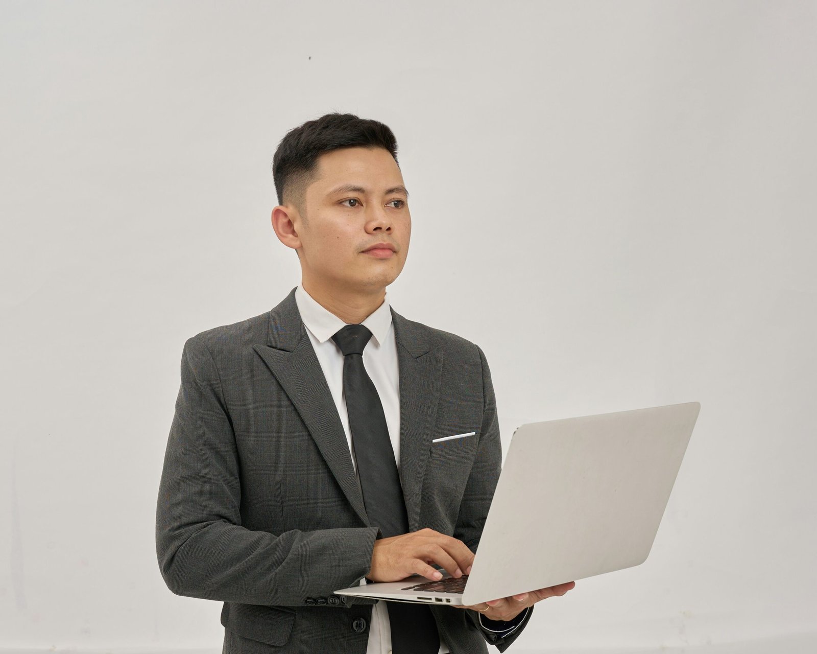Asian businessman holding a laptop while reviewing COE and PQP renewal figures for a commercial vehicle