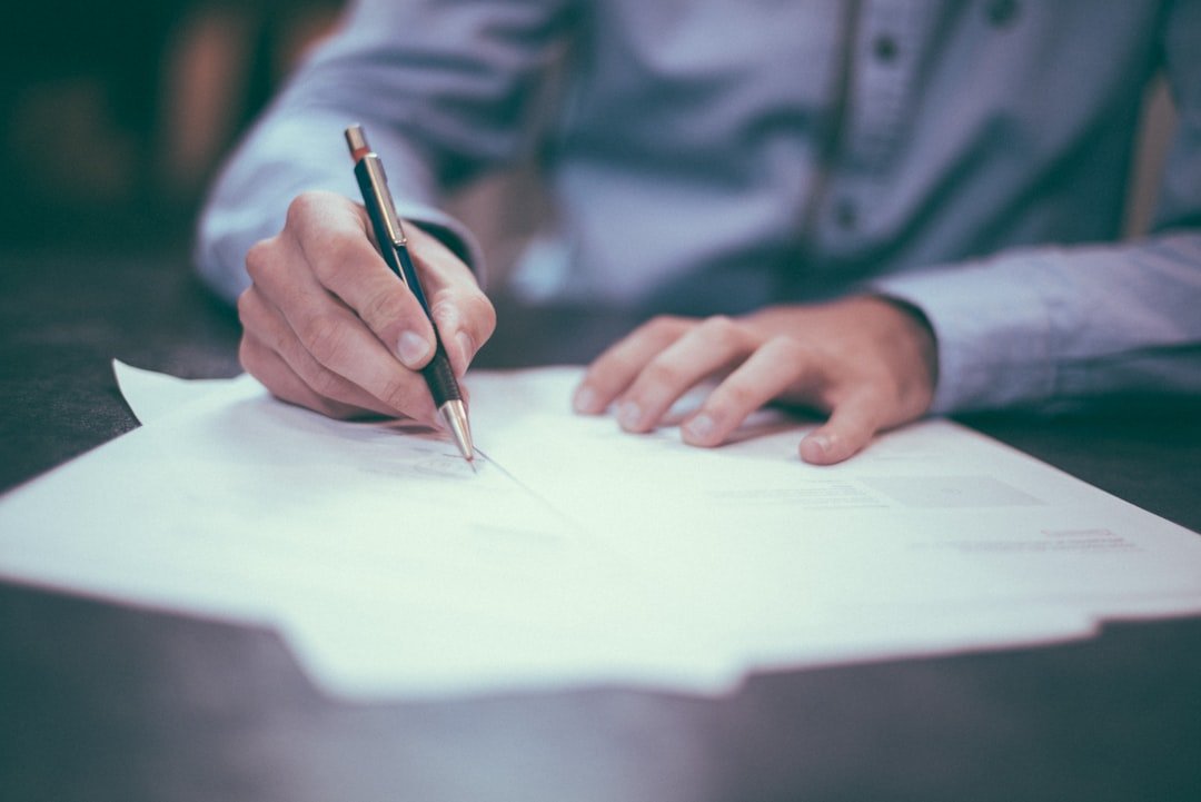 Close-up of a hand signing a commercial vehicle leasing contract, checking mileage cap and term details before signing in Singapore