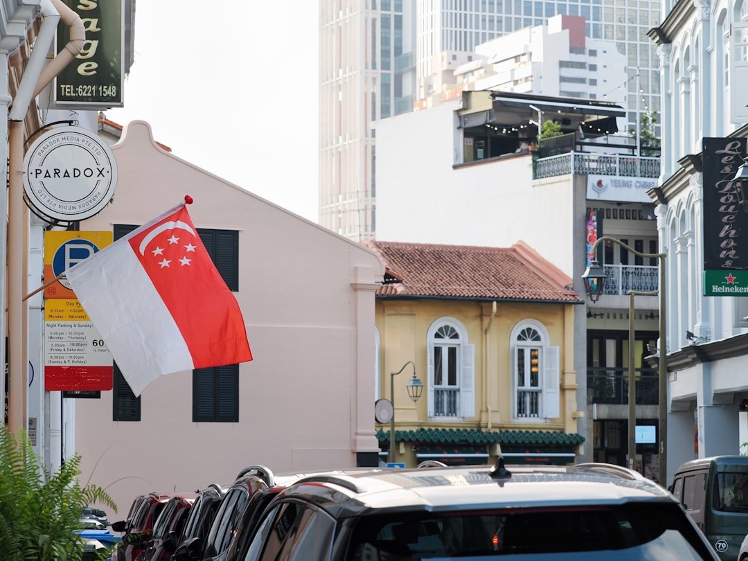 Singapore flag flying over a street of historic shophouses, representing traditional bank branches fleet operators visit for commercial vehicle loans