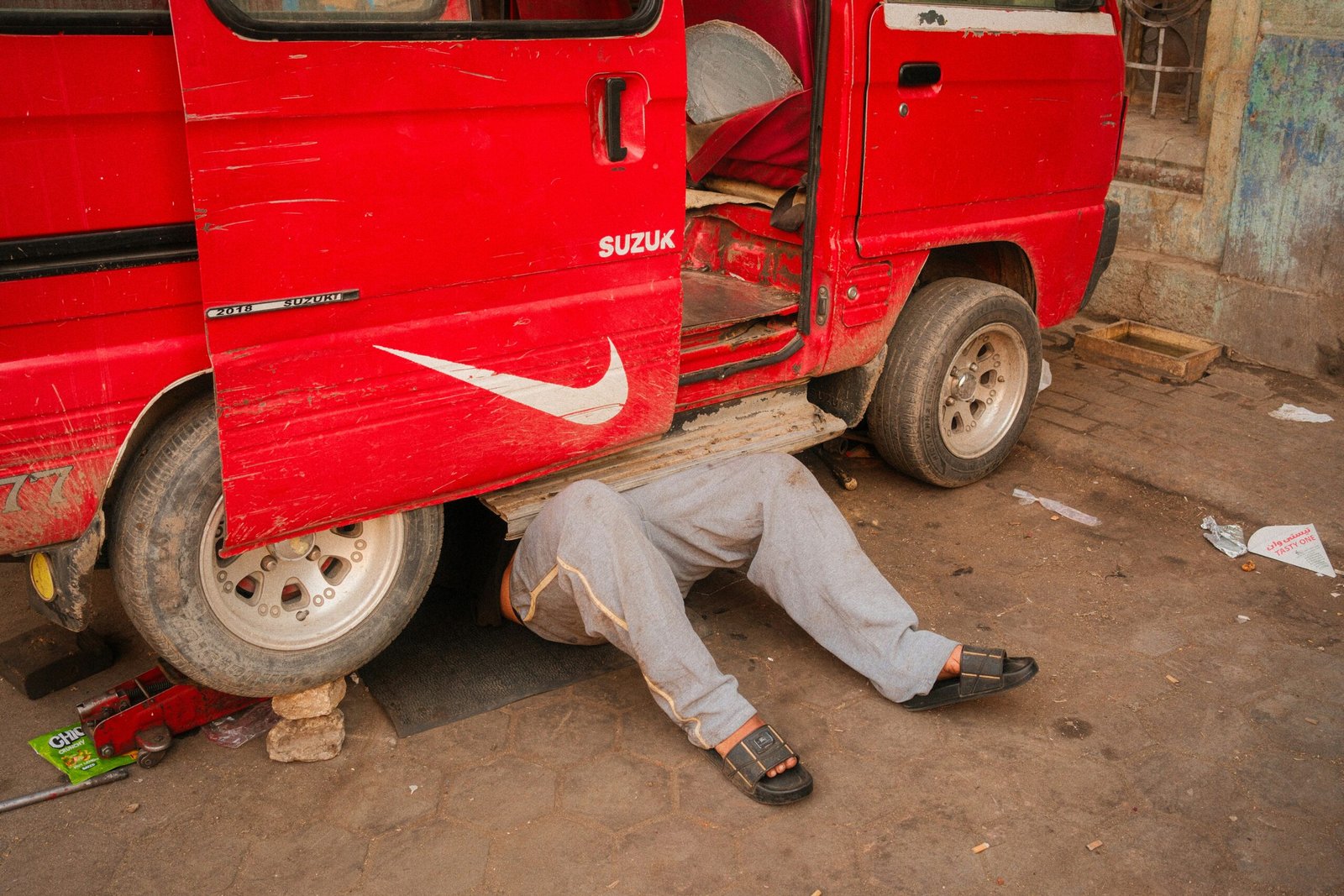Technician lying under a van to inspect underbody damage after a commercial vehicle accident repair